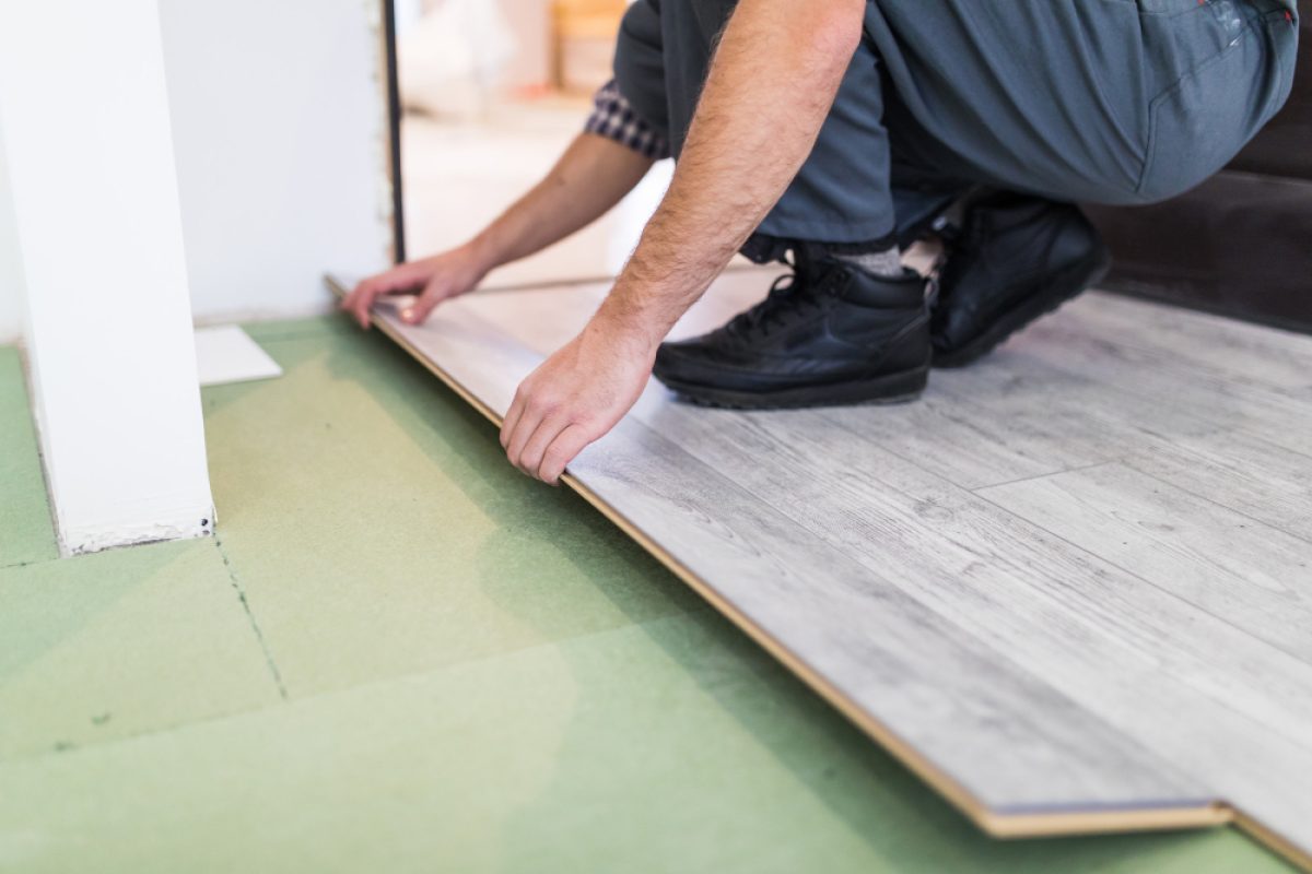 Person assembling furniture on a vinyl plank floor, surrounded by tools and materials, illustrating DIY projects and common mistakes to avoid when installing vinyl plank flooring.